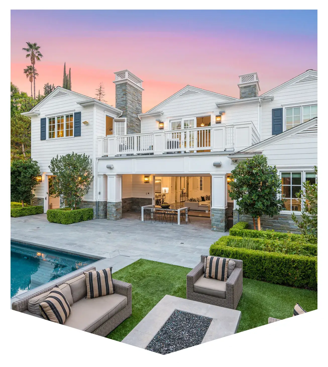 Elegant backyard with pool, fire pit, and cozy seating at sunset.
