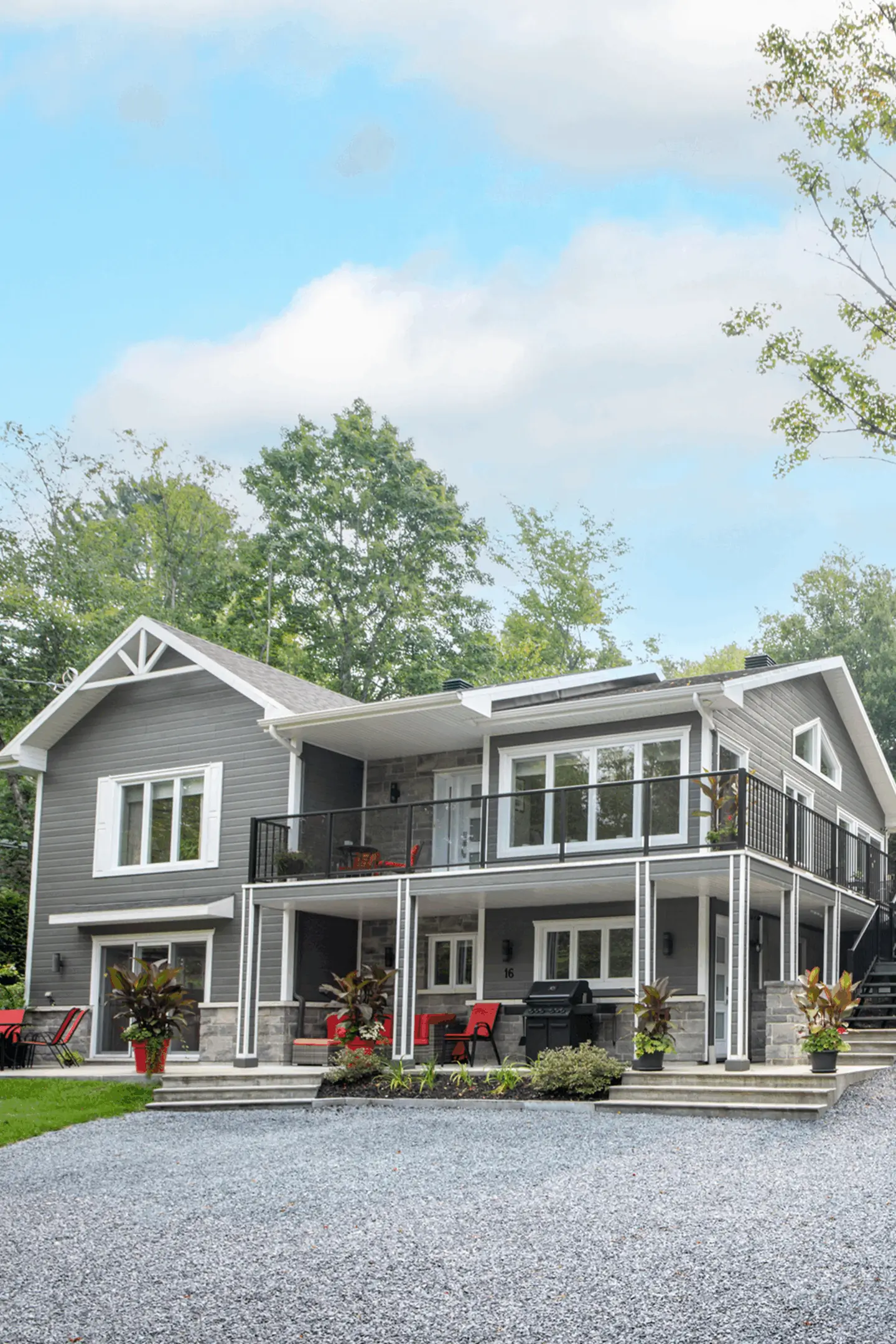 Modern two-story house with large windows and spacious balconies.